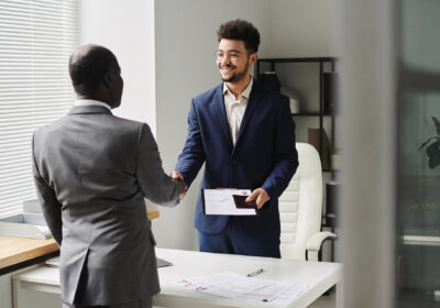 Specialist of visa center congratulating man of getting visa, they standing and shaking hands