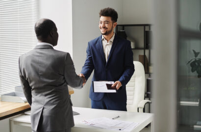 Specialist of visa center congratulating man of getting visa, they standing and shaking hands