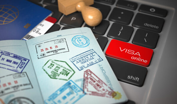 Visa online application concept. Open passport with visa stamps with airline boarding pass tickets and stamper on the computer keyboard. 3d illustration