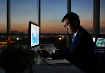 Serious Vietnamese businessman working on financial report in dark office