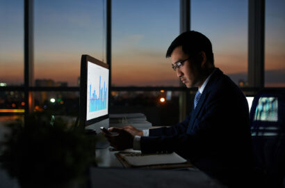 Serious Vietnamese businessman working on financial report in dark office